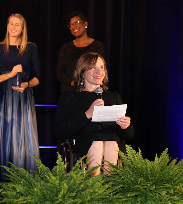 A gala honoree speaks from her wheelchair while accepting an award on stage